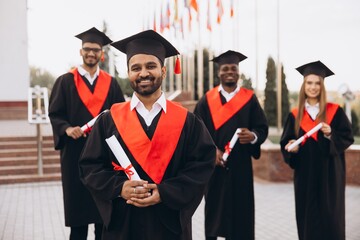 Diverse Group of Happy Graduates in Cap and Gown Celebrating Achievement Outdoors