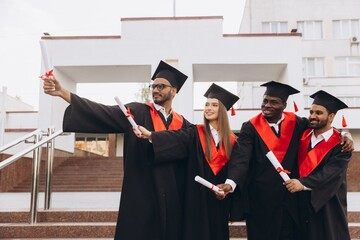Diverse Group of Happy Graduates Celebrating Achievement with Diplomas in Academic Caps and Gowns...