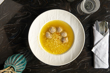 Portion of appetizing meatballs soup with star macaroni