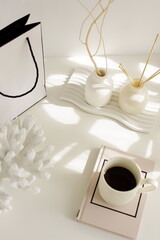 Aesthetic feminine desk stationery, modern fashion accessories, coffee cup, home decor, gift box mockup, vase with dry plant, candle top view on white table with sunlight shadows. Copy space