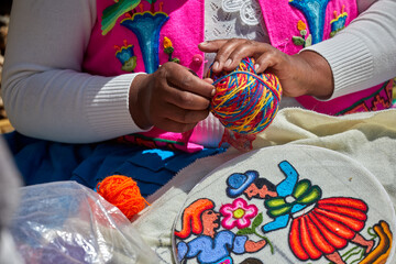 Fototapeta premium skillful Uros hands at work, delicately embroidering traditional Andean patterns. Each stitch reflects generations of cultural knowledge and artistic expression. Puno Peru