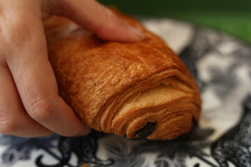 a close up photo of a hand holding a pain au chocolat