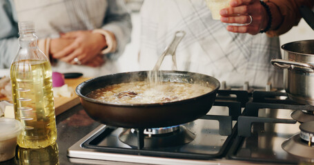 People, hands and cooking food in kitchen with recipe, add seasoning and meal preparation. Couple, dinner and pan on stove for simmering, nutrition and bonding in home with cuisine for wellness