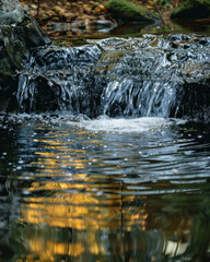 Obraz premium Small waterfall cascading over rocks into pool of water