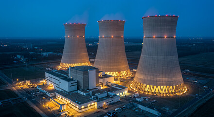Night view of nuclear plant with cooling towers illuminated creating contrast