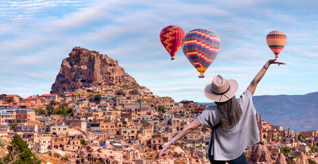 Beautiful young woman dressed in dark blue jeans with a beige hat - Hot air balloon flying over spectacular Cappadocia - Goreme, Turkey