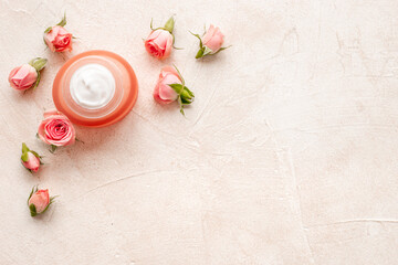Top view of pink roses and skin care cream with flowers essential oil