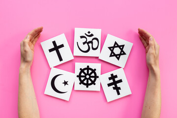 World religious concept. Hands holding Christianity cross, Islam crescent, Buddhism dharma wheel, Hinduism aum, Judaism David star symbols, top view