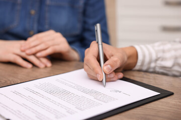 Man putting signature on document at table, closeup