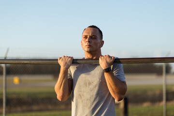 Young man performs a chin up at outdoor gym