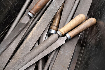 Old metal workshop tools. Vintage hand files with wooden handles. Industrial background with textured steel. Classic carpentry equipment. Rustic metalworking instruments in a toolbox closeup.