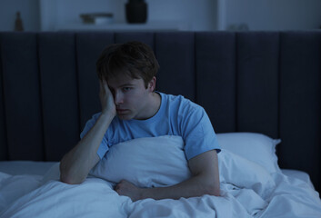 Frustrated man suffering from insomnia in bed indoors