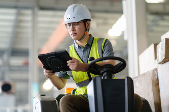 An Asian male worker is driving a forklift.