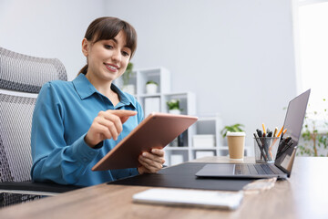 Woman using modern tablet at desk in office. Space for text