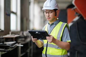 An Asian male engineer is using a digital tablet  in the factory