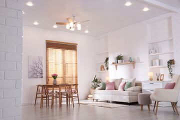 Stylish dining table with chairs and comfortable sofa in room. Interior design