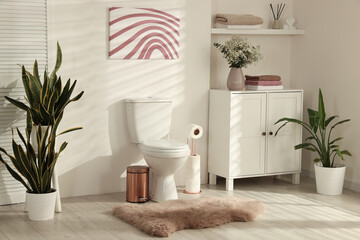 Ceramic toilet bowl, houseplants and necessities in restroom