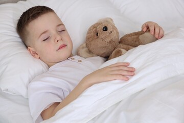 Bedtime. Cute boy sleeping with his teddy bear in bed