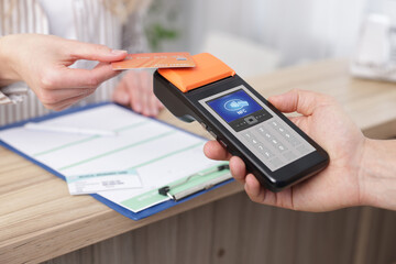 Payment terminal with NFC system. Client using credit card to pay for service indoors, closeup