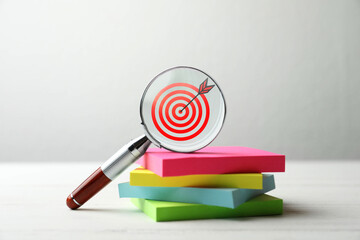 Targeting. Magnifying glass with bullseye inside and paper notes on table