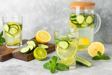 Cucumber water with lemon, lime and mint on a wooden table. Water infused with sliced ​​cucumber in a drinking glass. Tonic refreshing drink. Cucumber lemonade.Summer natural cooling drink.Copy space