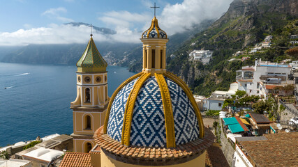 Closeup of colorful dome and tower bell of the church of San Gennaro in the main square of Praiano. This parish is located in the Amalfi Coast, Campania, Italy. In background is the town of Positano. © Stefano Tammaro