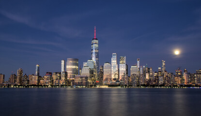 Obraz premium new york city skyline view during blue hour just after sunset (dusk nightfall night time photography from jersey city waterfront) hudson river downtown skyscrapers tall commercial buildings reflecting