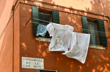 Cloths stretched to dry outside the windows of a colorful house at Fondamenta delle Case Nuove, in the sestiere of Cannaregio, Venice, Veneto, Italy