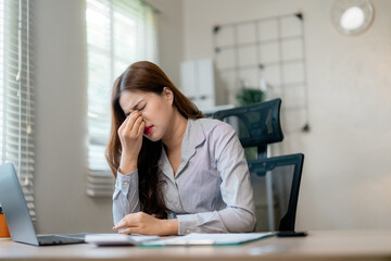 Fatigued businesswoman massaging temples, experiencing visual strain from prolonged screen time