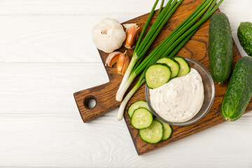 Cucumber sour cream tzatziki sauce on a wooden table.Tartar sauce. Traditional delicious appetizer. yogurt sauce. Tzatziki with ingredients cucumber, garlic,dill,lemon,mint. salad dressing.Copy space