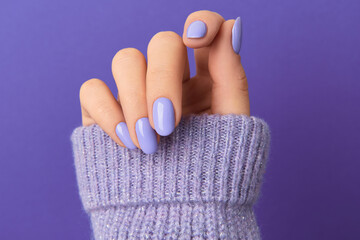 Manicured womans hand in sweeter on violet background. Manicure, pedicure beauty salon concept