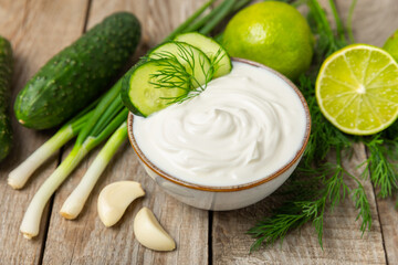 Cucumber sour cream tzatziki sauce on a wooden table.Tartar sauce. Traditional delicious appetizer. yogurt sauce. Tzatziki with ingredients cucumber, garlic,dill,lemon,mint. salad dressing.Copy space