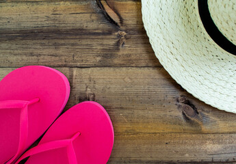 Summer vacation, flatlay. Hat and flip flops on a dark wooden background.