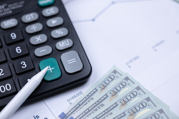 Calculator, pen, and banknotes on a financial document, symbolizing budgeting and accounting.