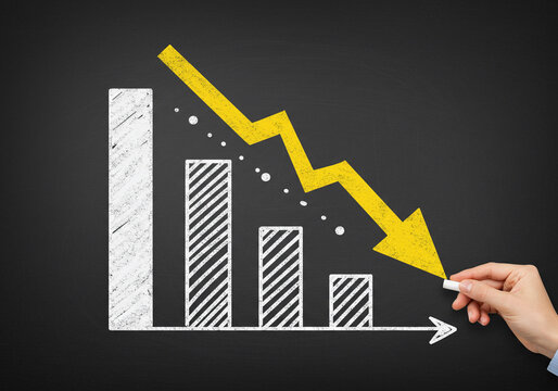 A downward yellow arrow touches a hand on a chalkboard, visually representing a decline alongside descending white bar charts and dots.
