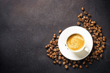Coffee cup and coffee beans at dark table .