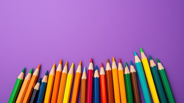A vibrant collection of colorful pencils arranged neatly on a solid purple background provides ample copy space.