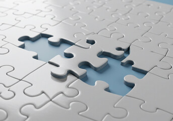 Obraz premium A partially finished white jigsaw puzzle lies on a blue surface with missing pieces and scattered individual pieces nearby. 