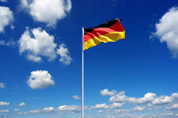flag of Germany fluttering in the blue sky with cumulus clouds