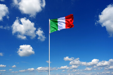 flag of Italy fluttering in the blue sky with cumulus clouds