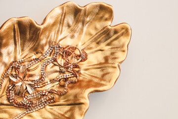 Elegant jewelry arranged on a decorative golden leaf dish in a bright setting