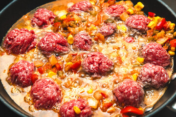 Cooking meatballs in a savory stew with vegetables and spices on a stovetop