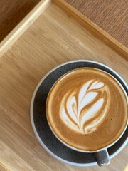 A cup of hot latte coffee on a wooden table taken using a high angle cafeine breakfast 