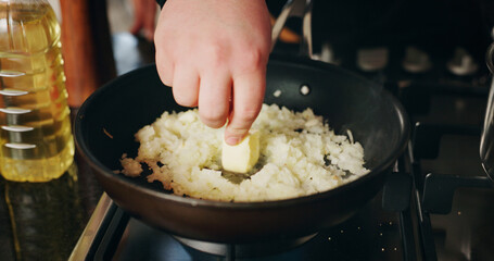 Butter, cooking and hand of person in kitchen of restaurant closeup for diet, health or nutrition. Gas stove, ingredients and pan with chef in hotel for gourmet cuisine, hospitality or service