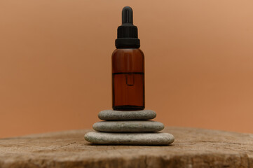Cosmetic oil in a glass container on pebbles. On a wooden surface.