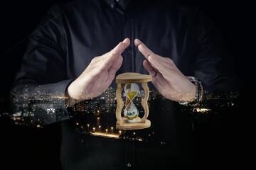 Man holds hourglass with city lights in background