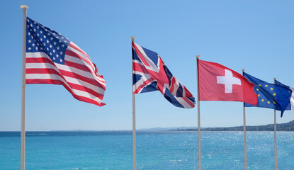 The flags of the United States, Great Britain, Switzerland, and the European Union in the wind at the coast of Nice, France