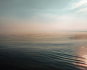Obraz premium Silent Seascape: The calm expanse of the sea stretches towards the hazy horizon under a serene, slightly overcast sky, evoking a sense of tranquility and vastness.