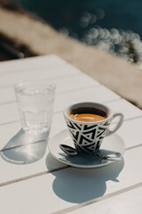 Cup of black coffee and a glass of water on a table in a street cafe in a sunny morning.