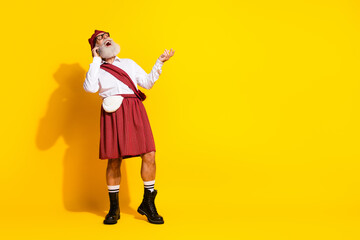 Elderly Man in Traditional Scottish Attire Posing Against a Vibrant Yellow Background, Wearing a Tartan Kilt and Plaid Accessories